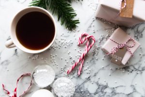A tabletop with Christmas presents, candy canes, garland, and a cup of coffee