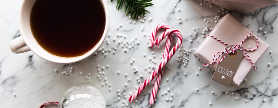 A tabletop with Christmas presents, candy canes, garland, and a cup of coffee