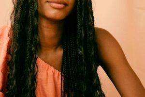 strong black woman posing in front of orange background