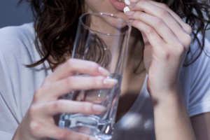 Woman holding white abortion pill up to her mouth